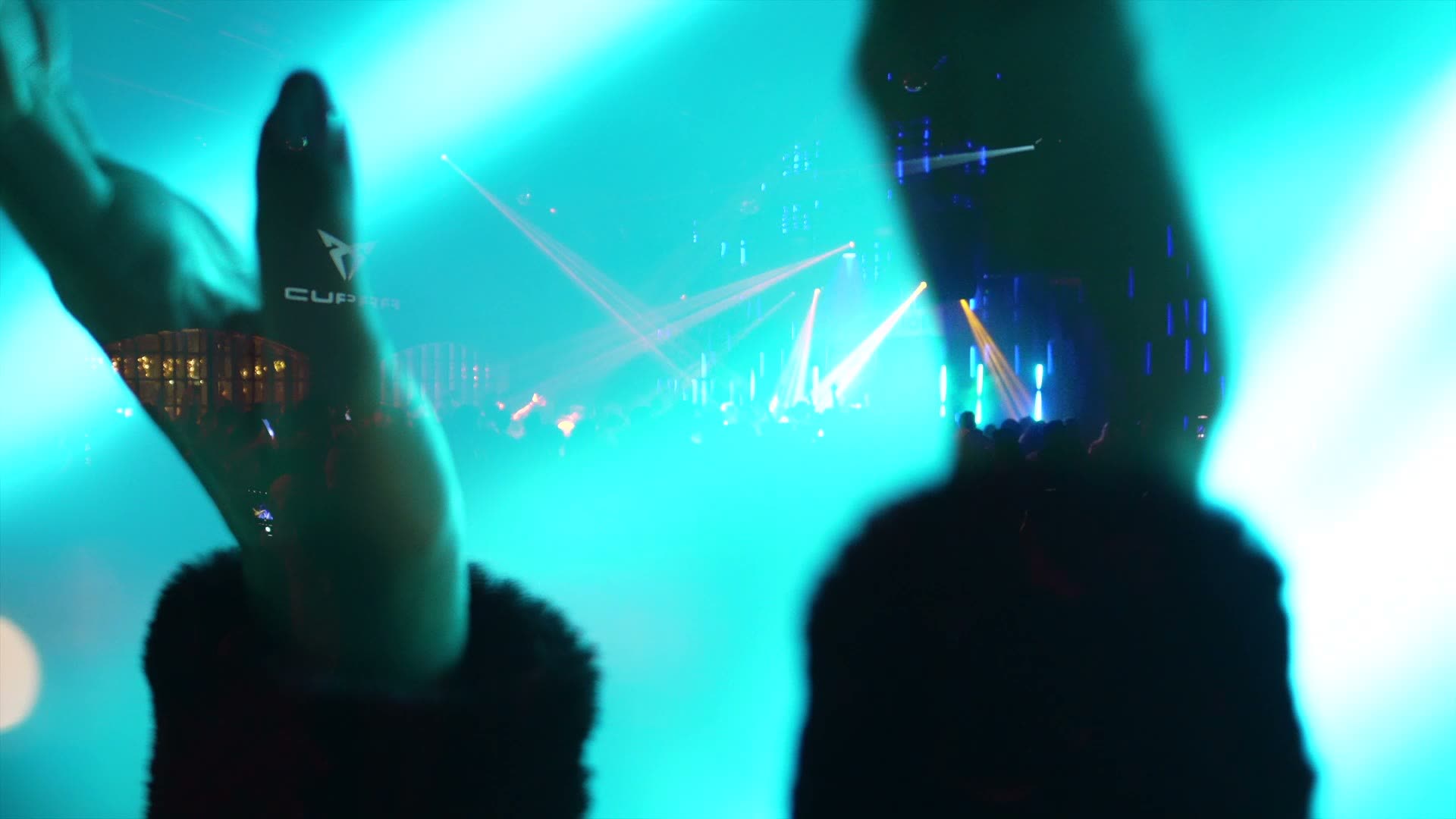 Concert lighting in teal over a silhouetted crowd