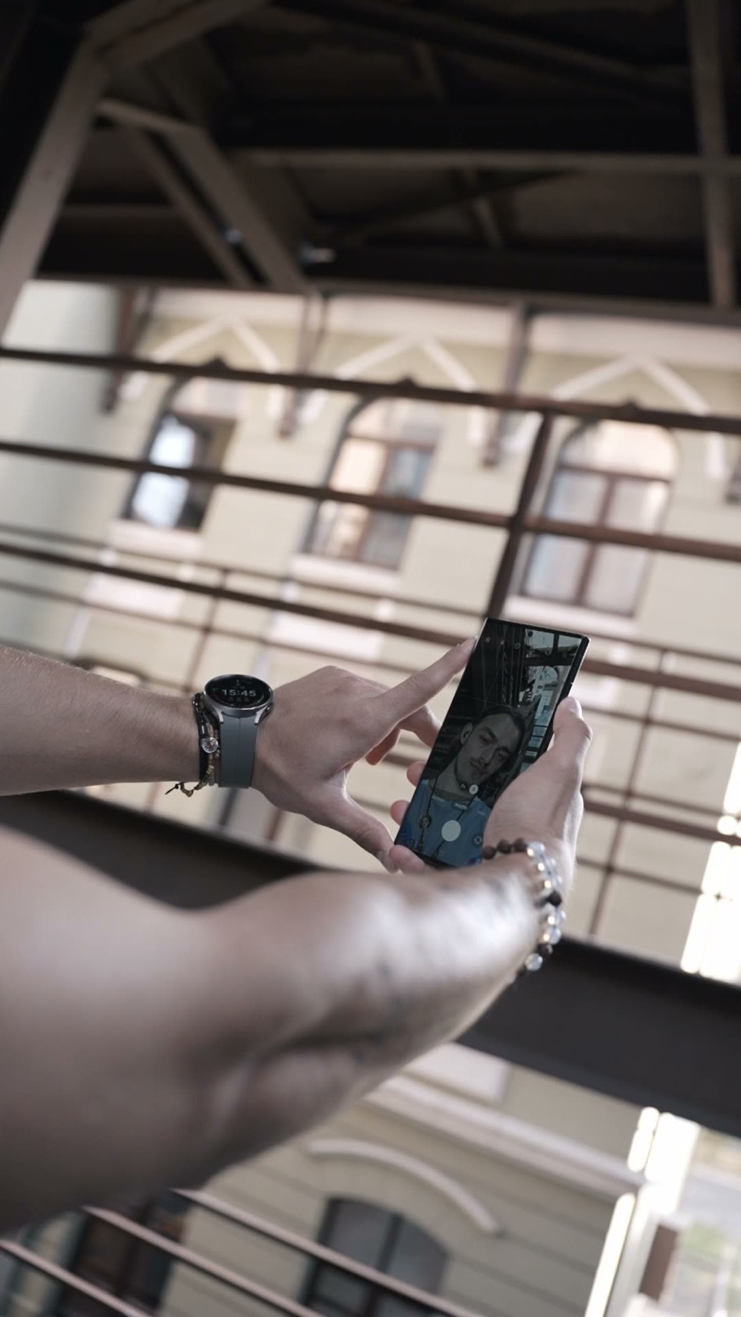 Hands filming with a phone, a smartwatch on the wrist